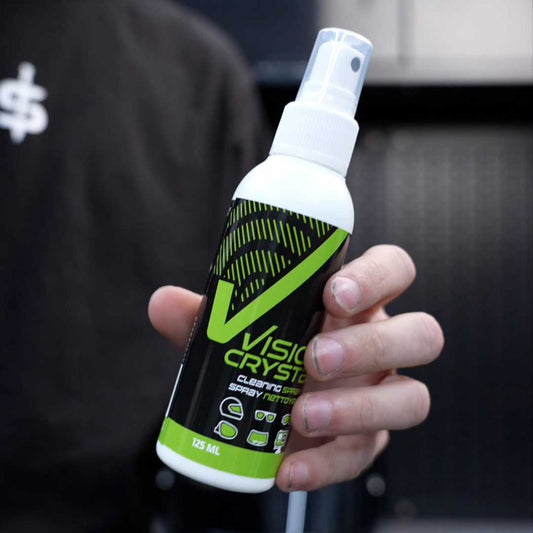 Hand holding a bottle of Vision Crystal spray with a blurred background