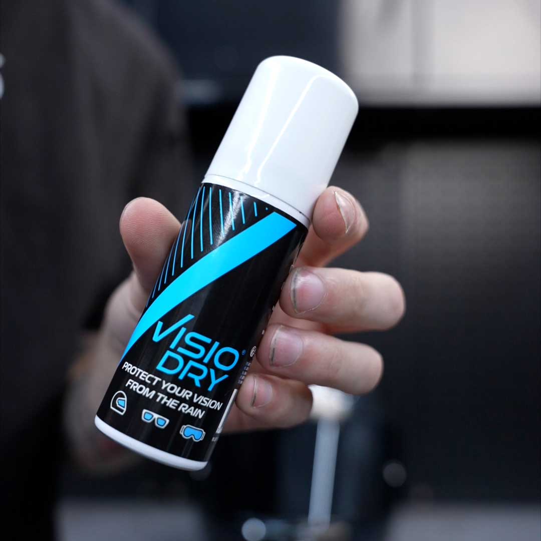 Hand holding a bottle of 'VisioDry' against a blurred background